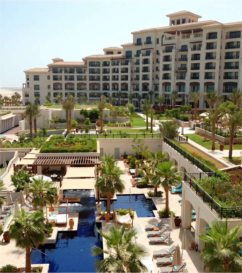 Bird eye view of a hotel with palms and swimming pools